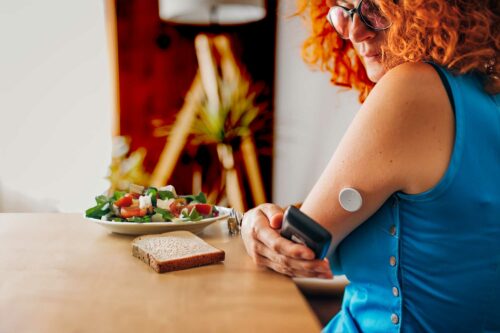 Woman in blue top using a flash glucose monitoring system